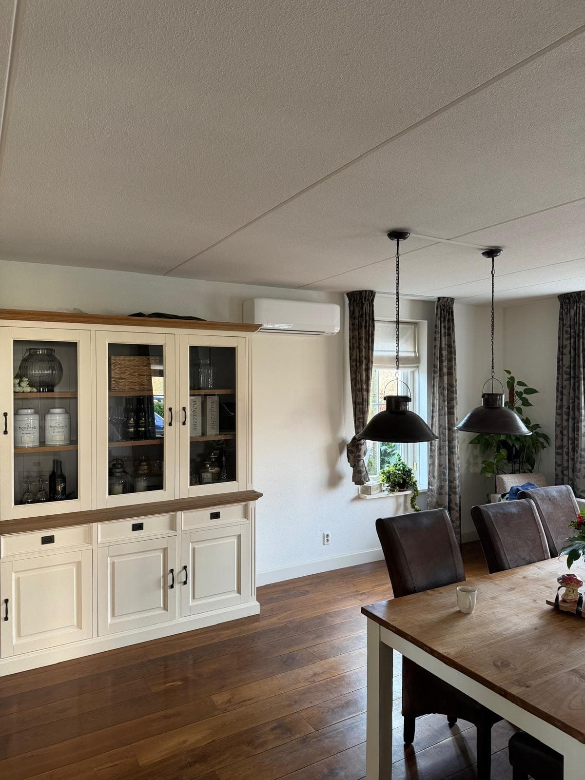 Wit airco-binnendeel boven een kast in de woonkamer