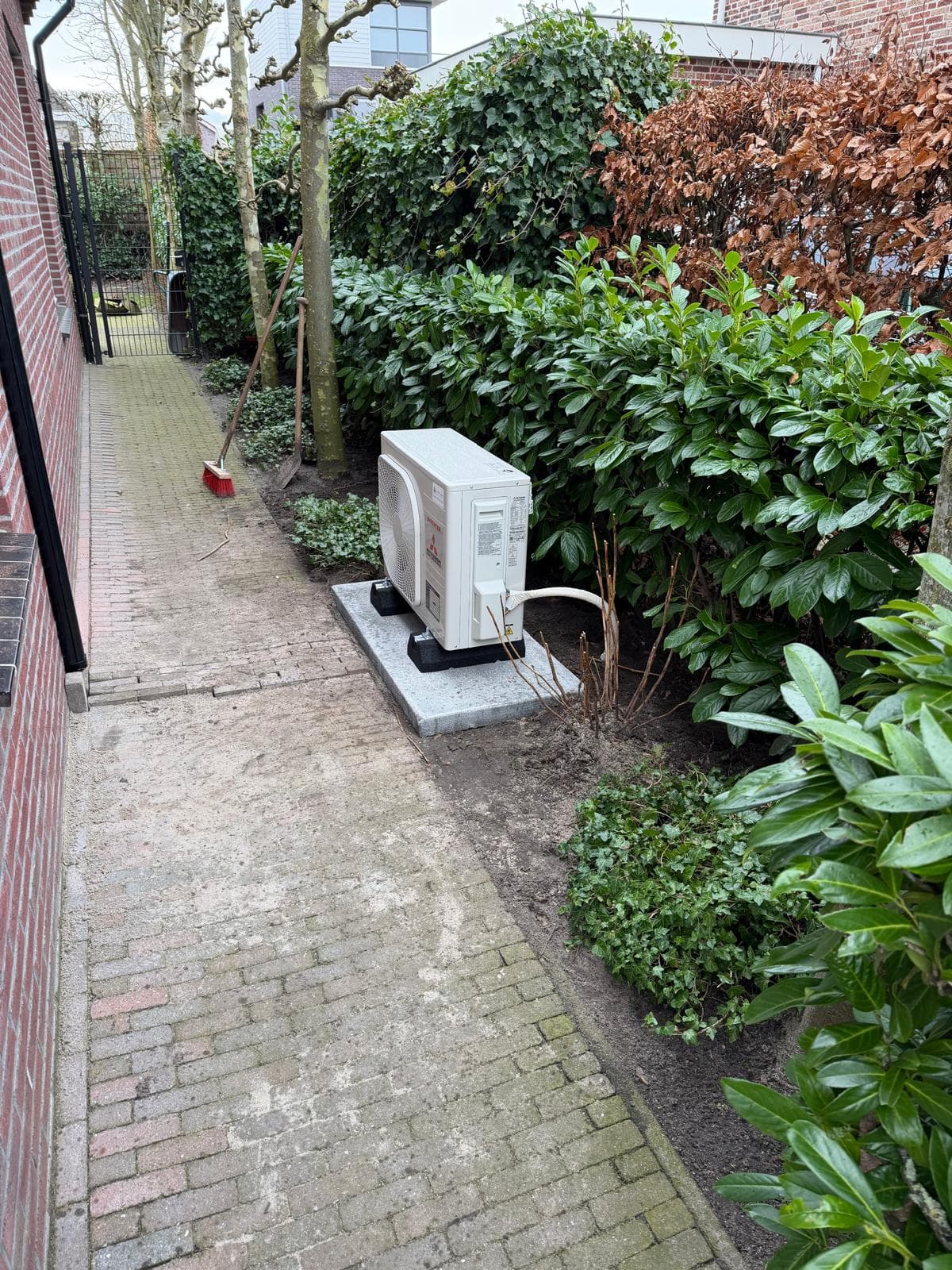 Airco-buitendeel op een betonplaat in een achtertuin