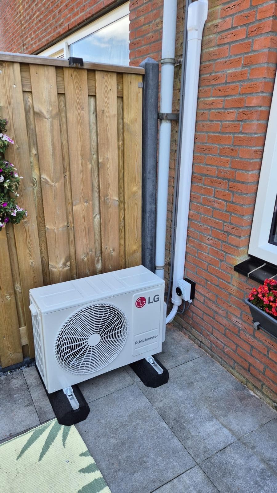 LG airco-buitendeel op poten naast een woning