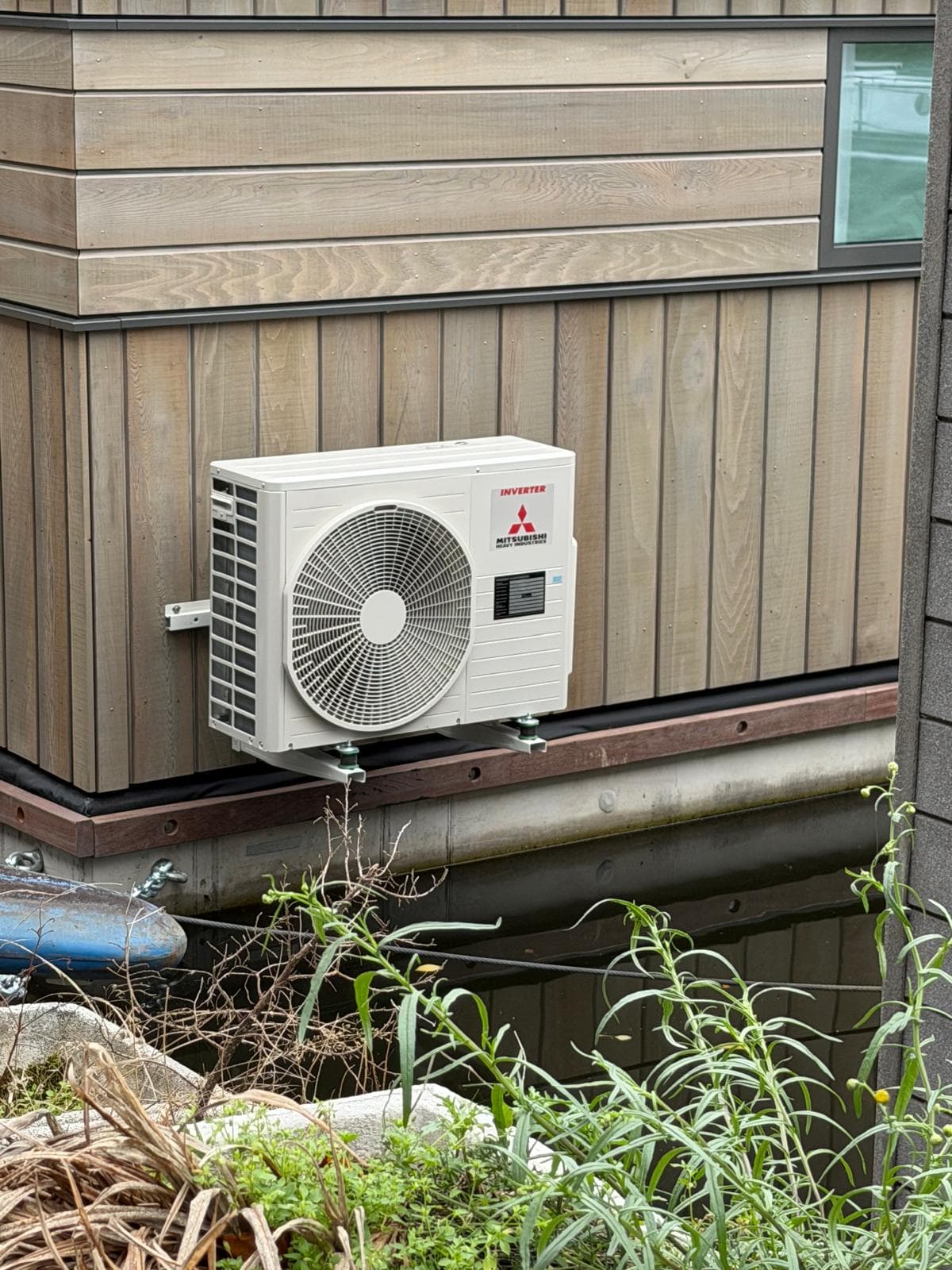 Mitsubishi airco-buitendeel op een beugel aan de kopse kant van een woonboot