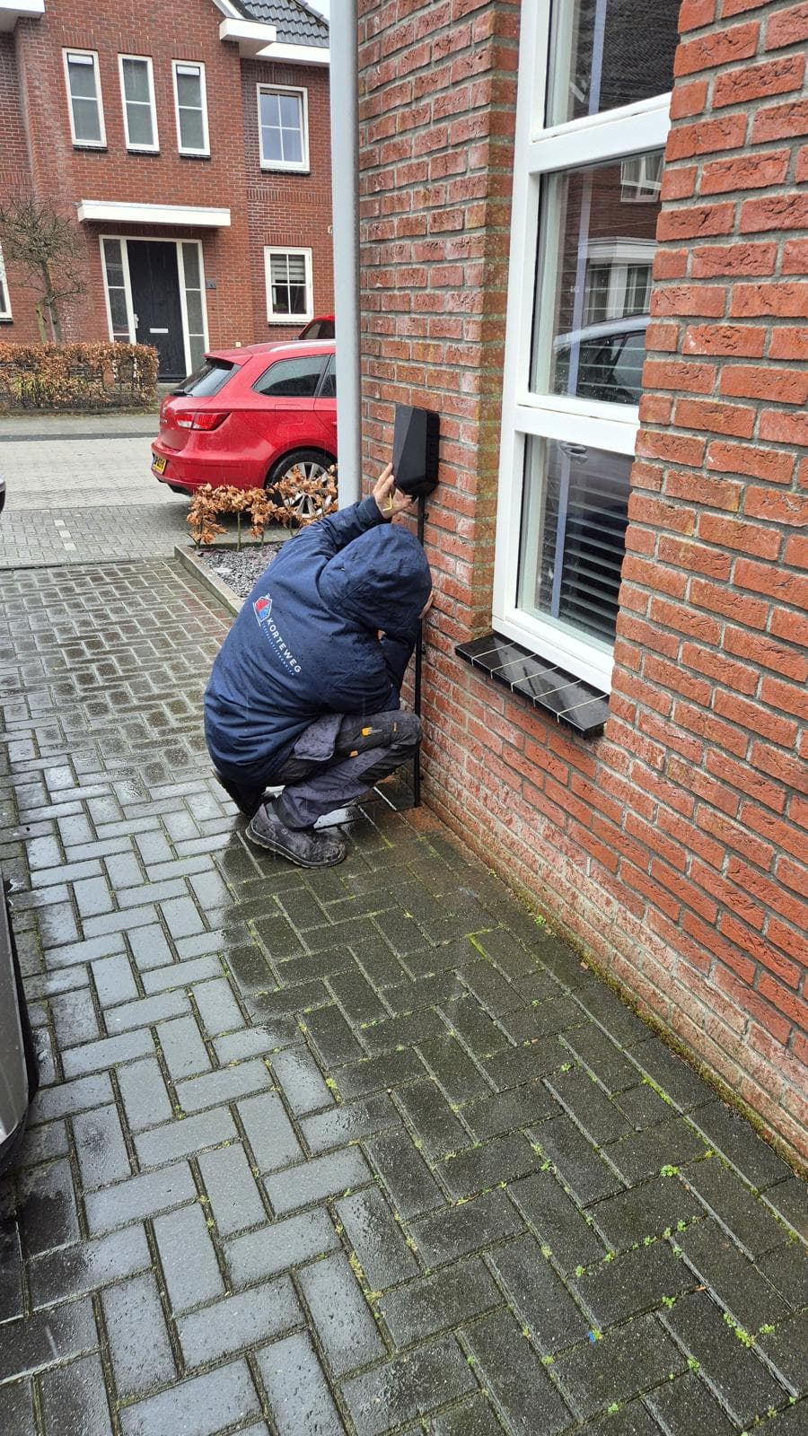 Monteur van Korteweg Techniek aan het werk bij de gevel van een woning